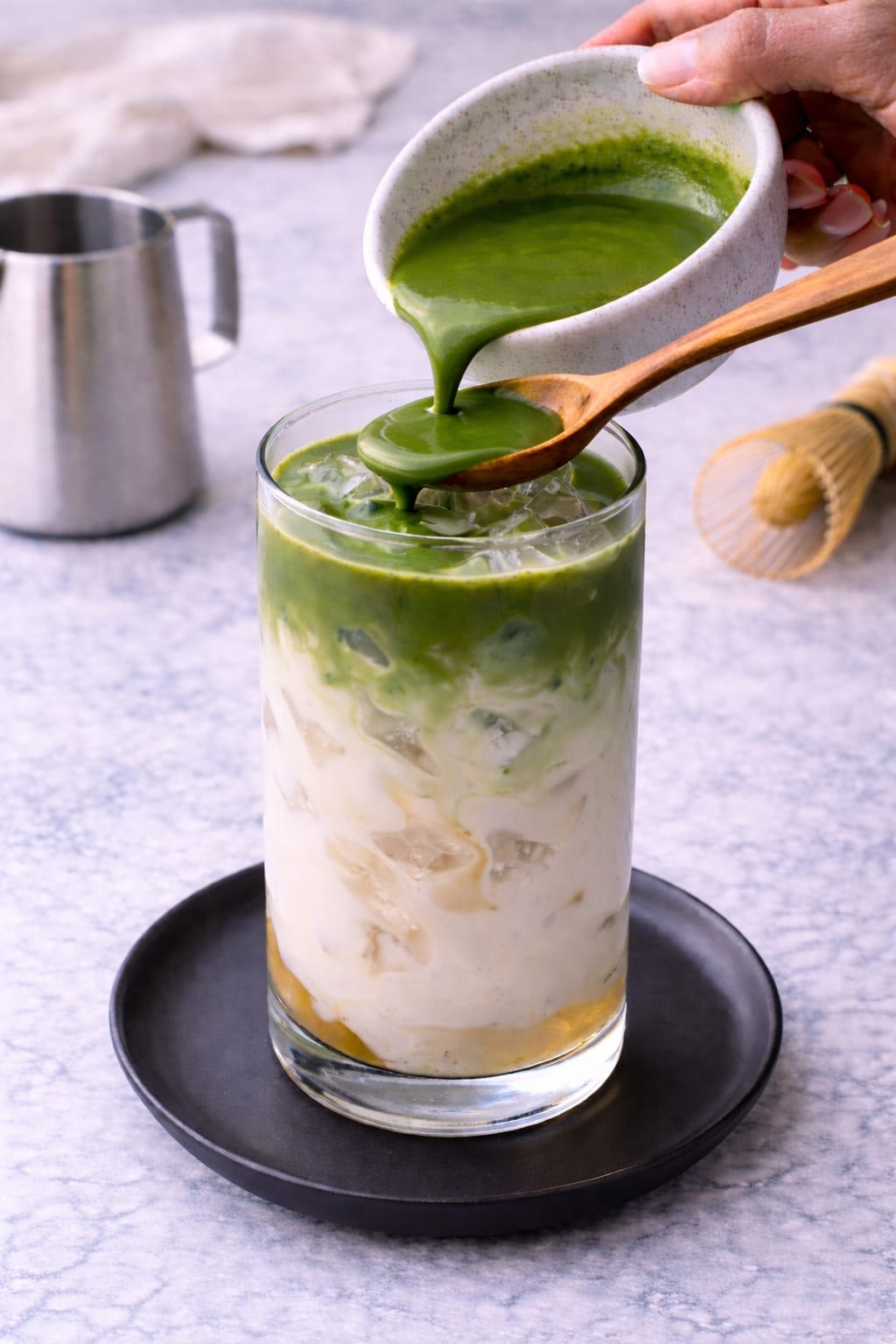 Step 5: Pouring whisked matcha into the glass to create a layered iced matcha latte