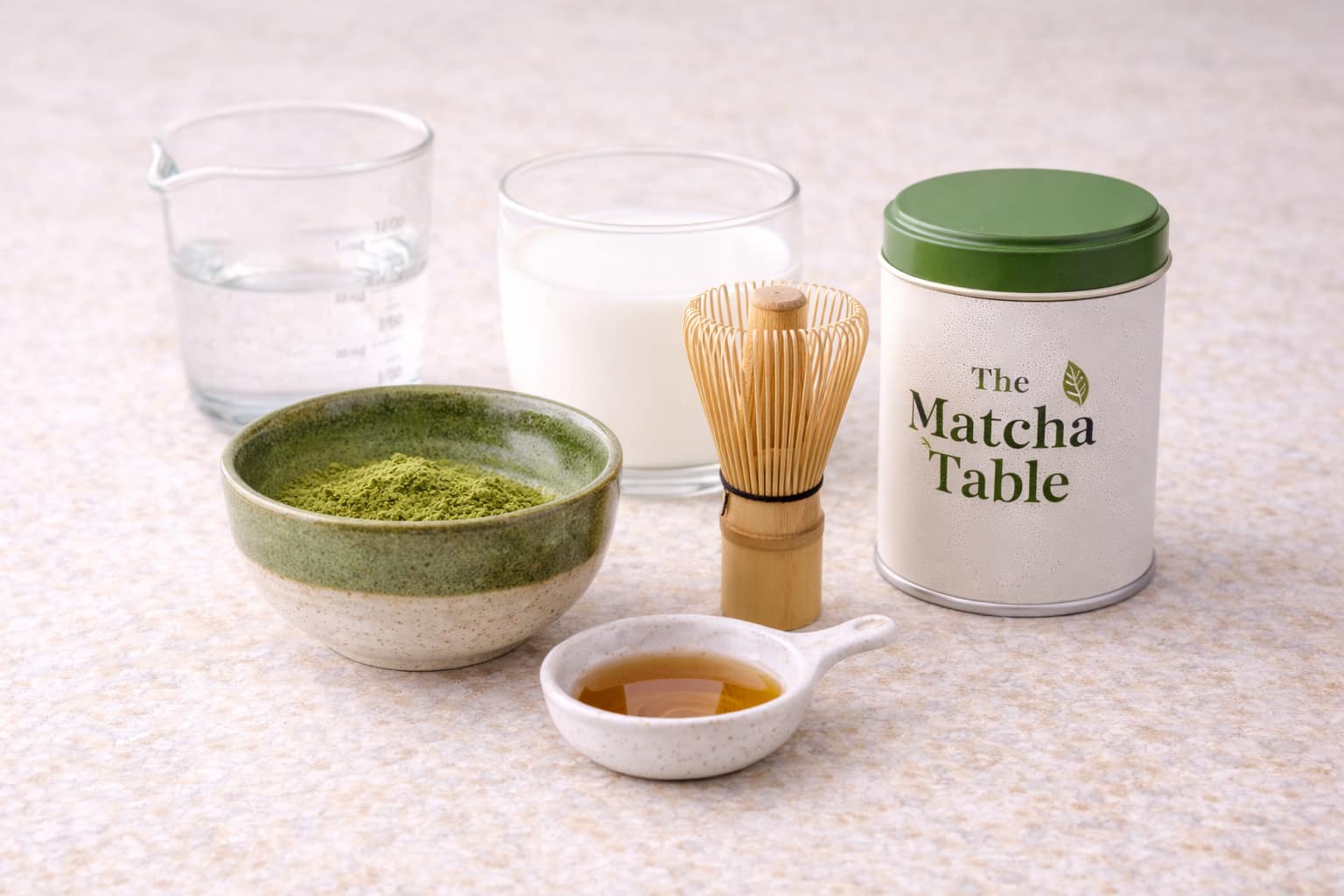 Ingredients for a homemade matcha latte including matcha powder, milk, hot water, and sweetener